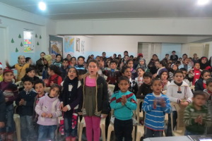 Syrian refugee children clap and sing about the birth of Jesus before their meal